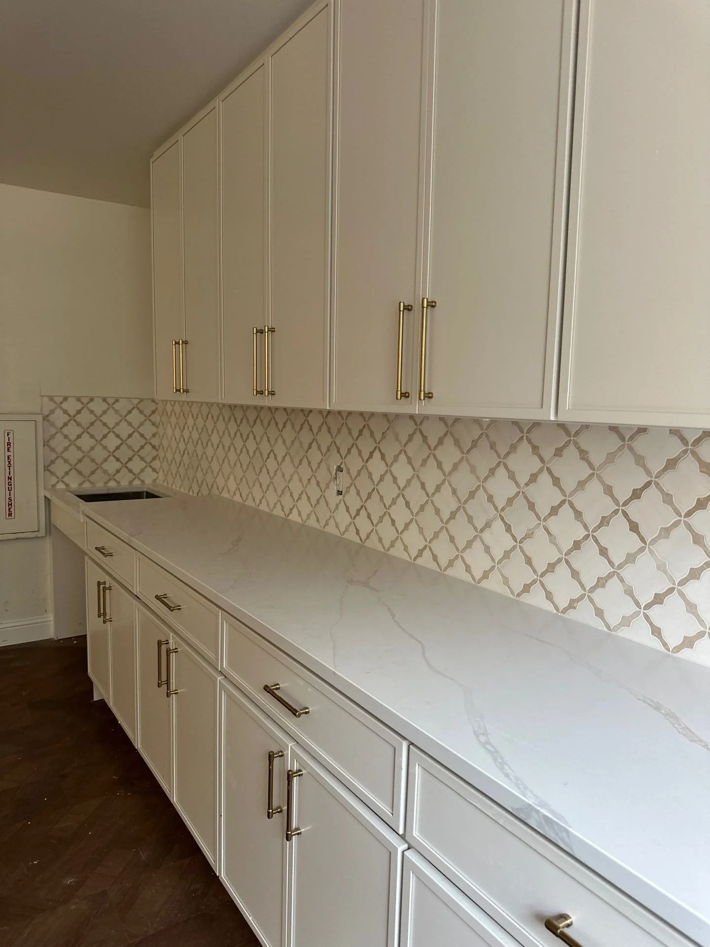 Senior living kitchenette with white shaker cabinets, quartz counters, and arabesque tile backsplash