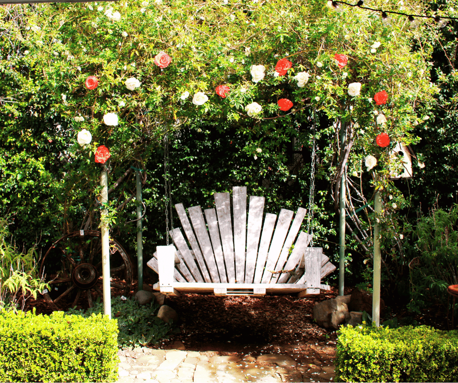 Beautiful Backyard ceremony site with a decorated hanging garden bench and floral arch above it