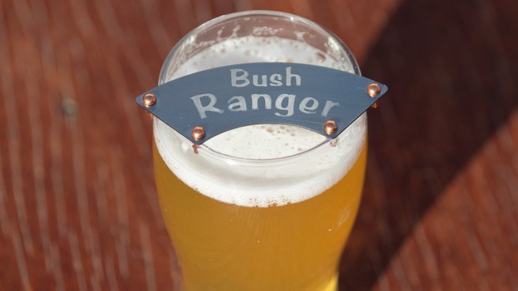 A glass of light beer topped with a device labeled 'Bush Ranger.'
