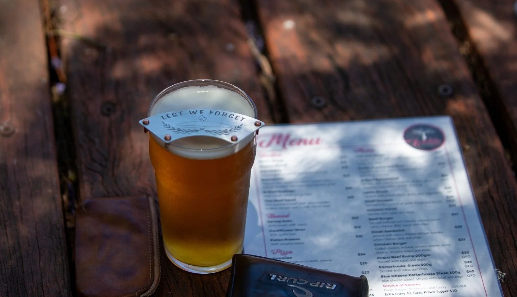 TiMelly moustache guard lest we forget version on a pint of beer beside a menu.jpg