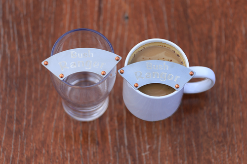 Glasse and mug, one empty and one filled with coffee, each with a "Bush Ranger" moustache on them.