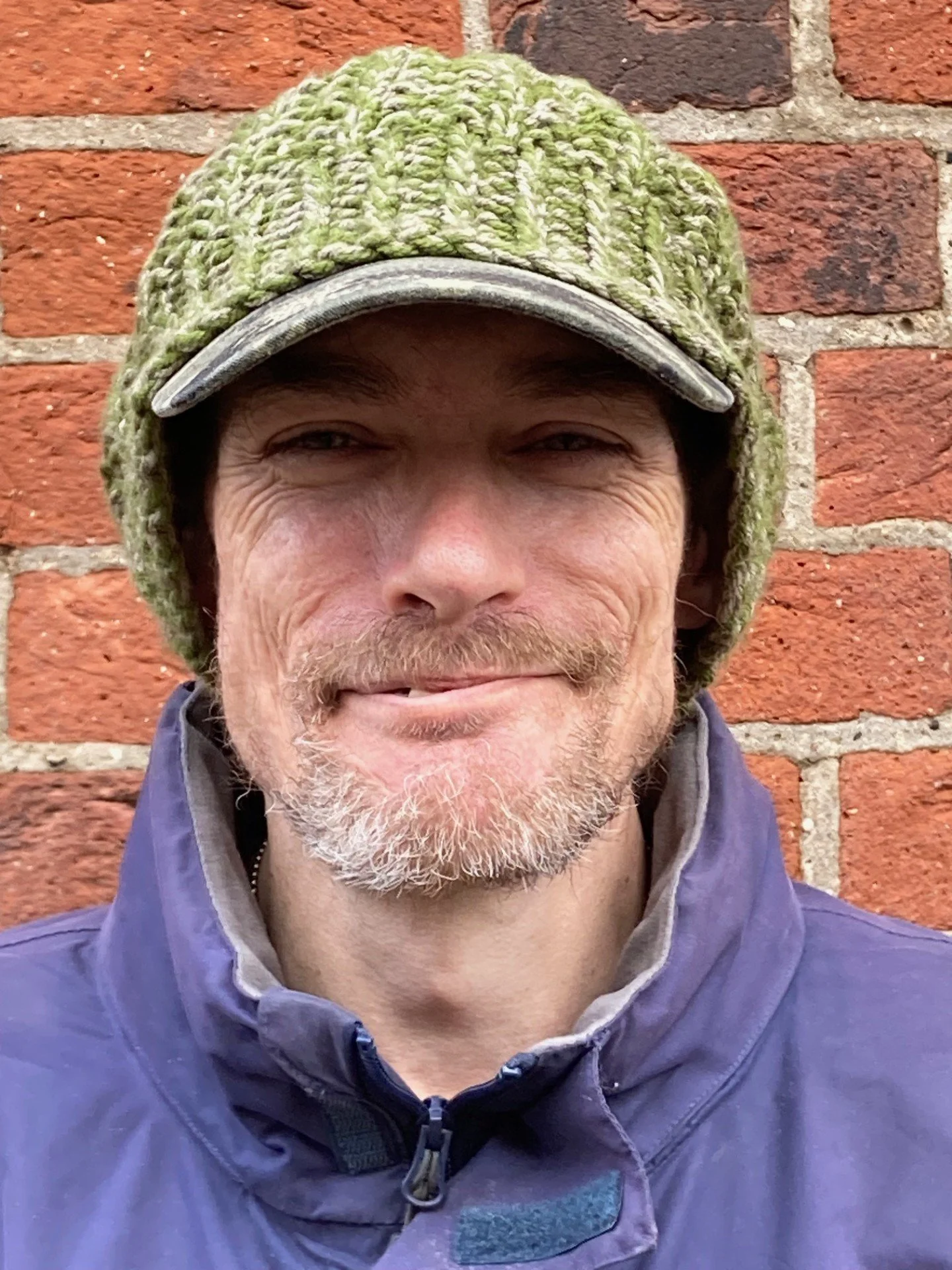 Bearded man smiling, wearing a green woolly hat