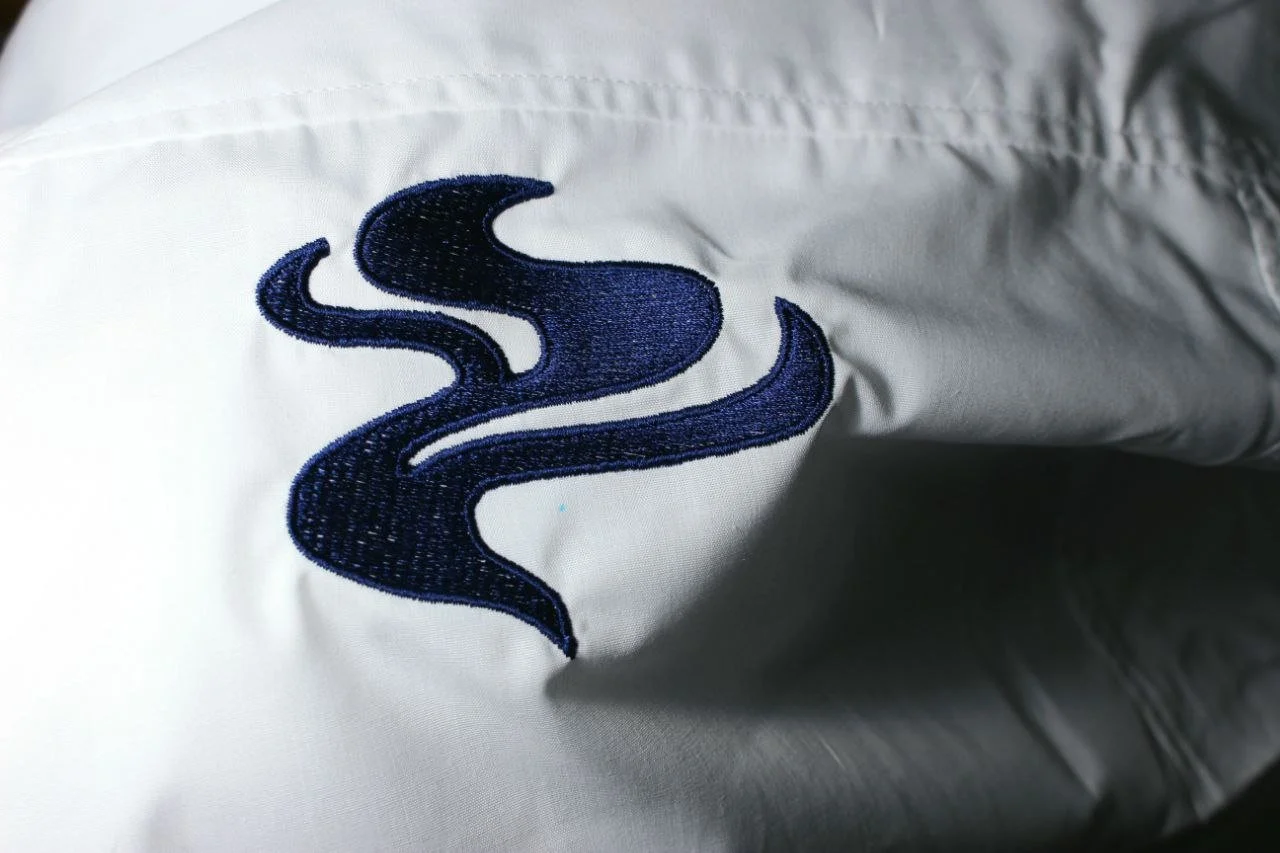 Ricamo di un'icona di fumo di colore blu su tessuto bianco.