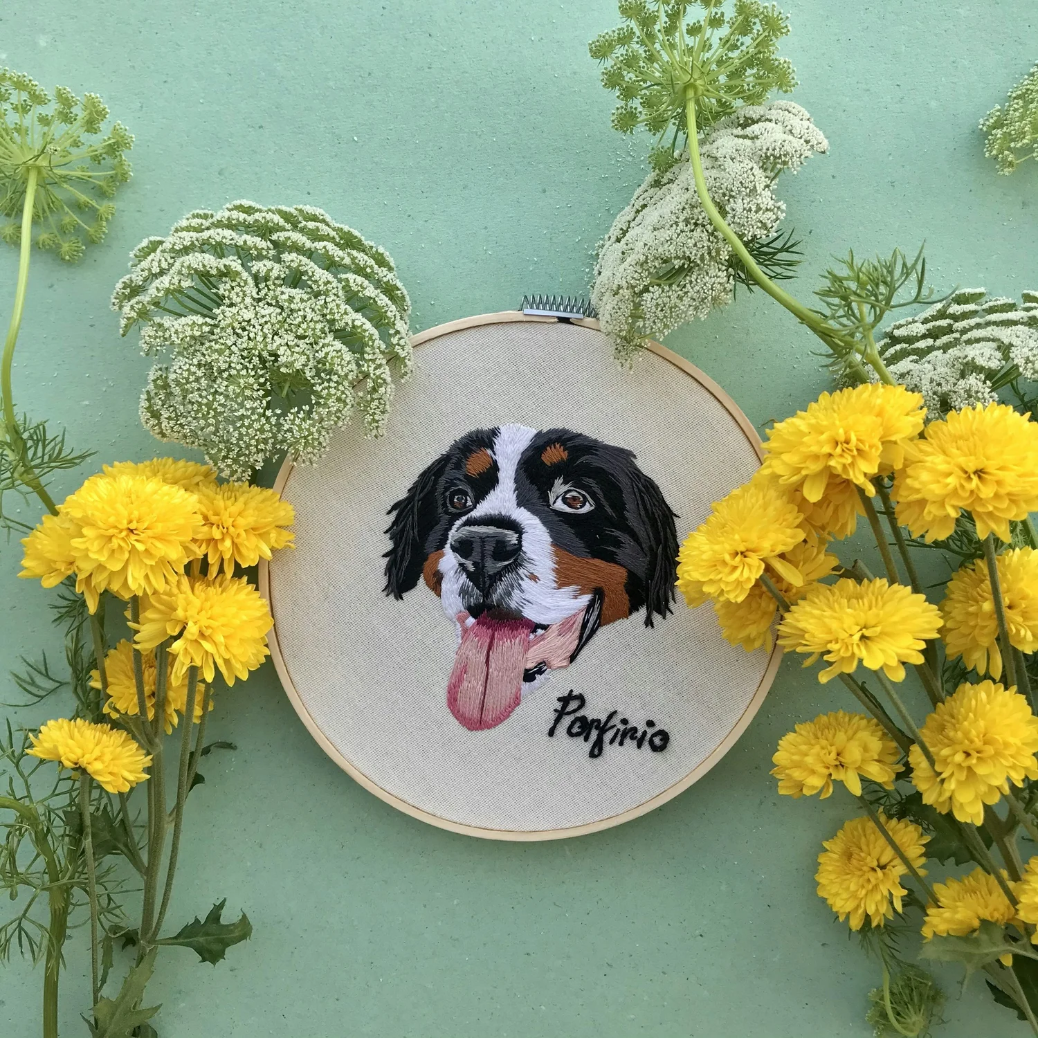 Ricamo di un cane circondato da fiori gialli e bianchi