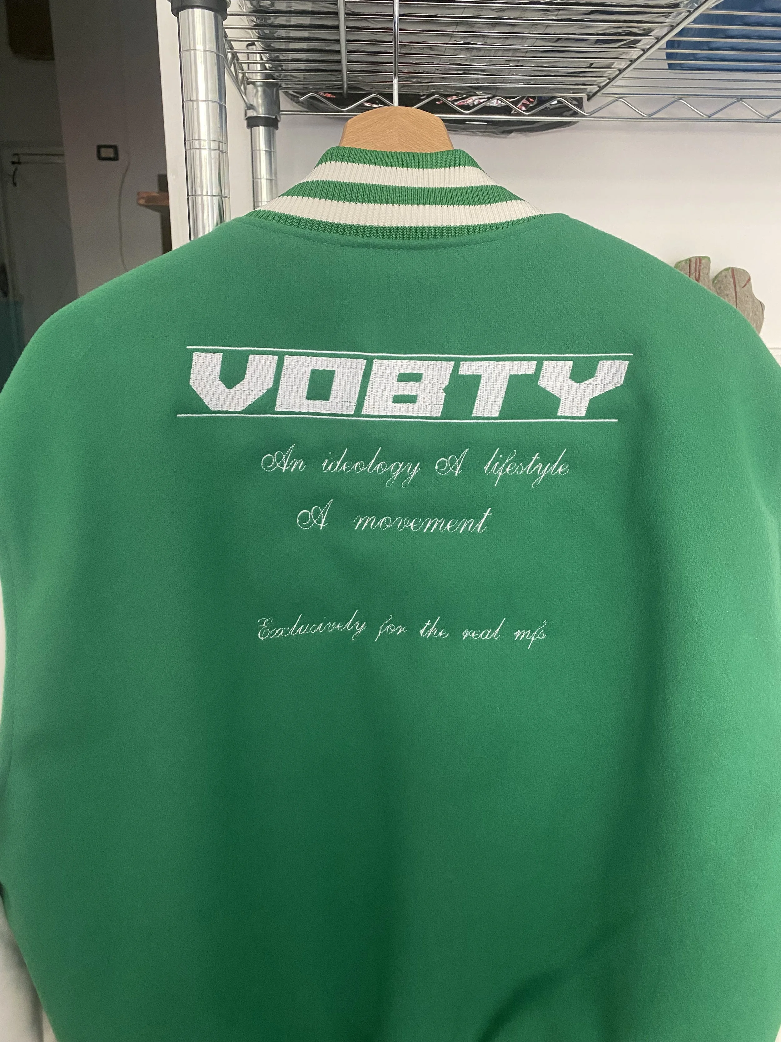 Una felpa verde con scritte apparecchiate. Il testo include la parola 'VOBTY' e una frase in corsivo che dice 'An ideology of lifestyle, A movement, Exclusively for the real me'.