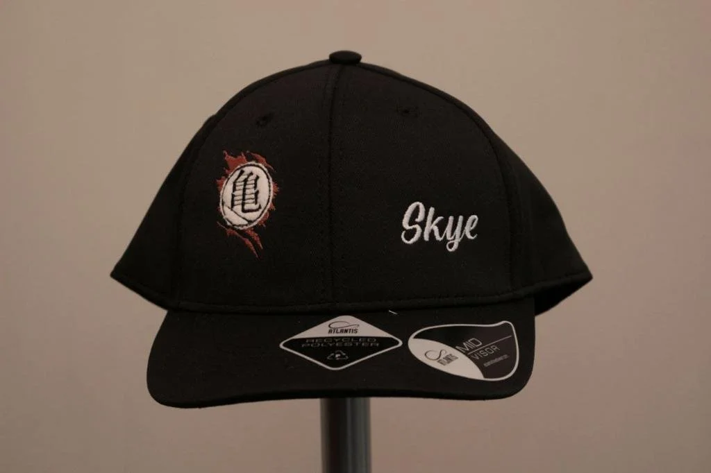 Cappello nero con ricamo Diavolo e scritta Skye, esposto su un supporto.