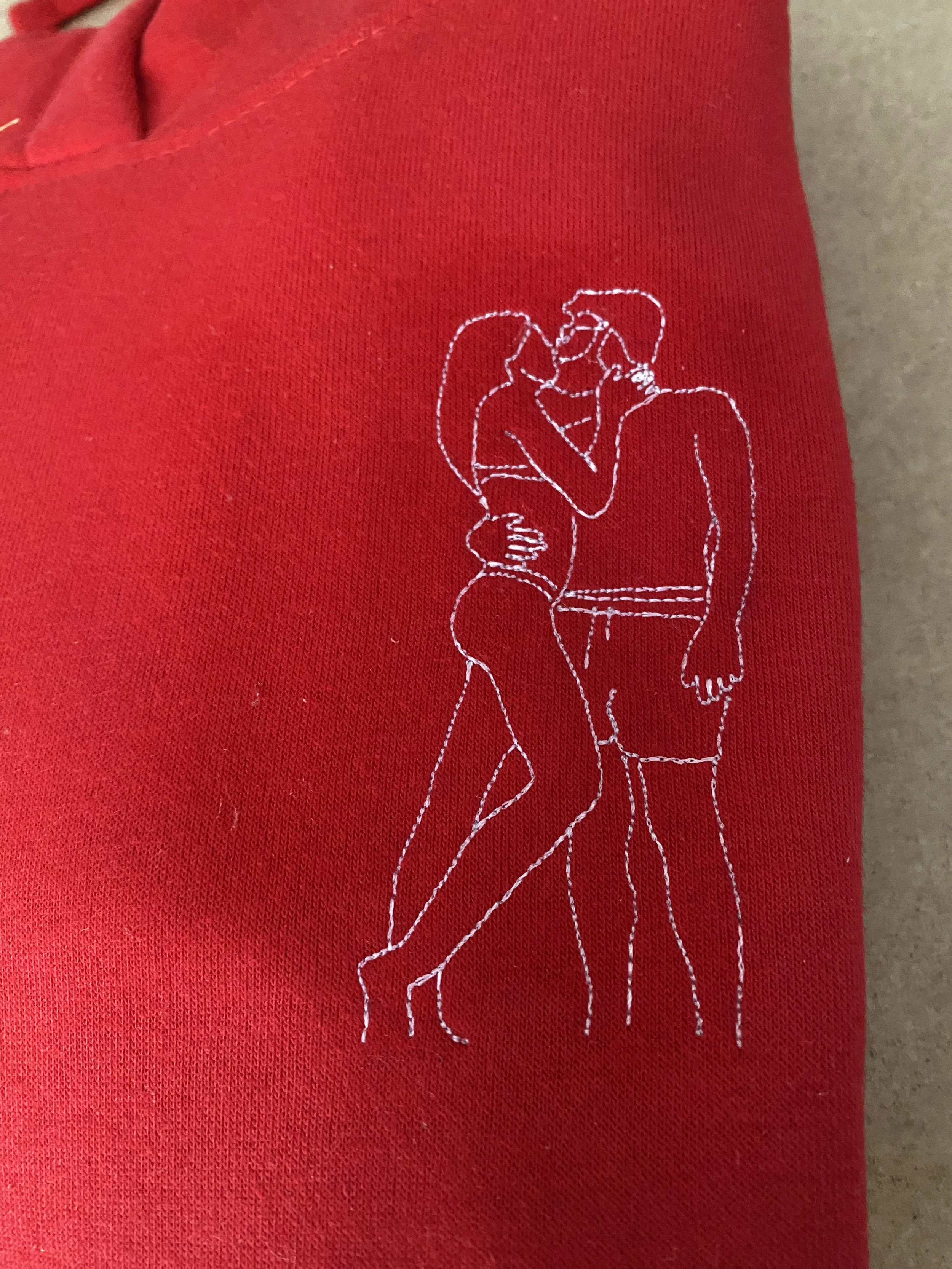 Line art di una coppia che si bacia, con la donna in piedi e l'uomo con le mani sui fianchi, su sfondo rosso.