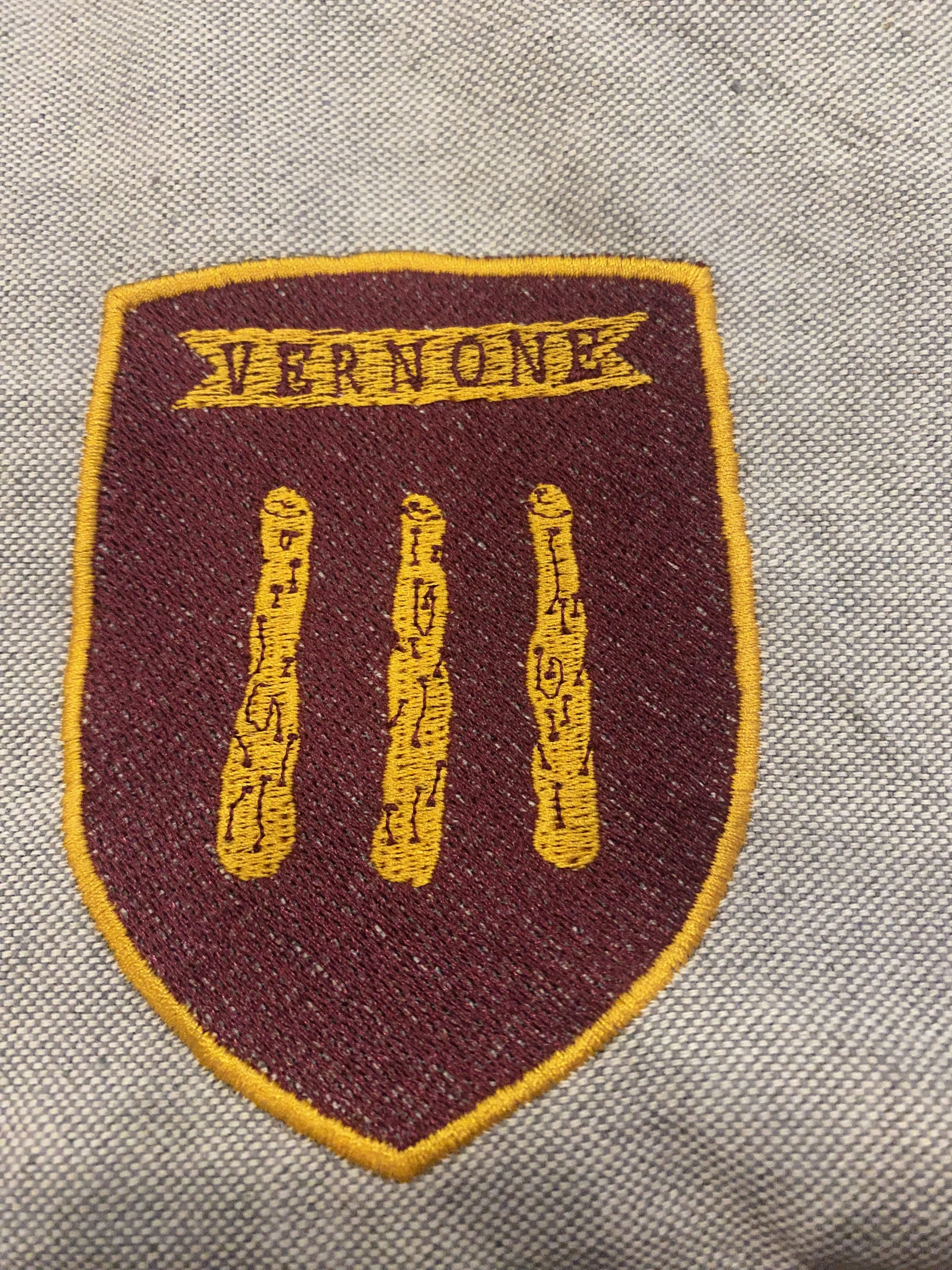 Badge patch con le parole 'Vermon' in alto, tre dita gialle con scritte nere, di colore rosso e bordo giallo.