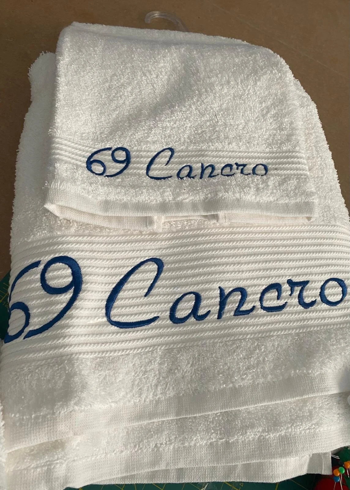Asciugamani bianchi con ricami in blu con la scritta '69 Cancro'