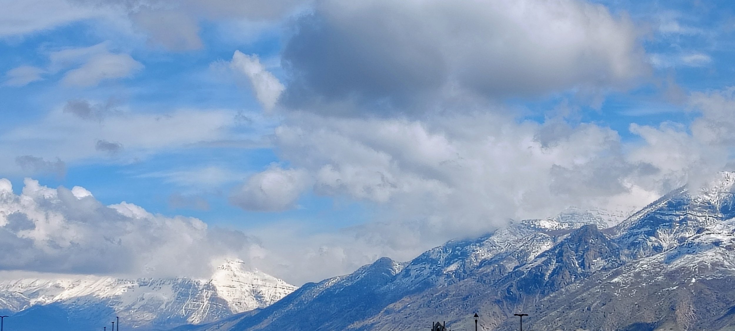 Snow-capped mountains under a partly cloudy sky with blue and gray clouds.