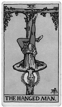 A Tarot card titled 'The Hanged Man' depicting a man hanging upside down by one foot from a tree, with a calm expression, dressed in robes, with a halo behind his head.