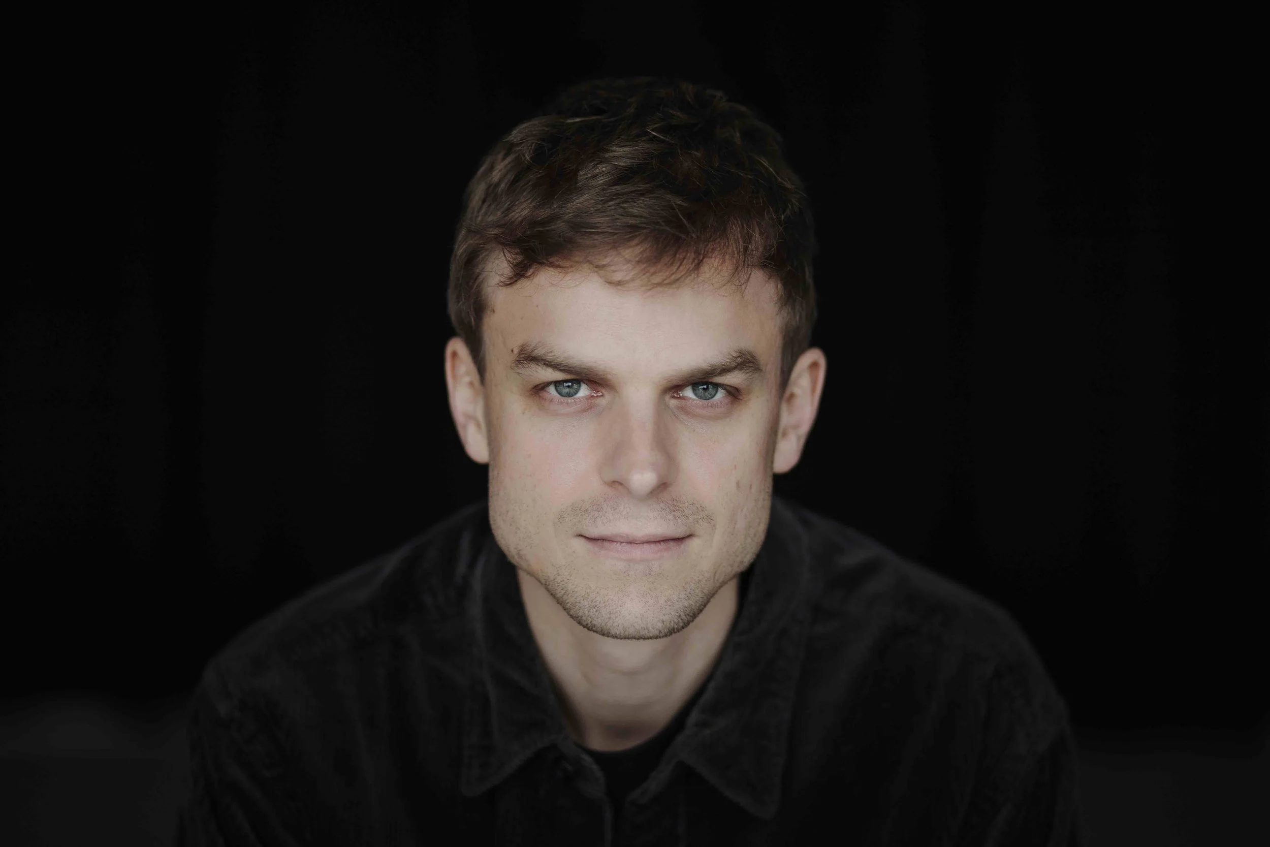 Bild von Max Santner mit schwarzem Hemd und schwarzem Hintergrund