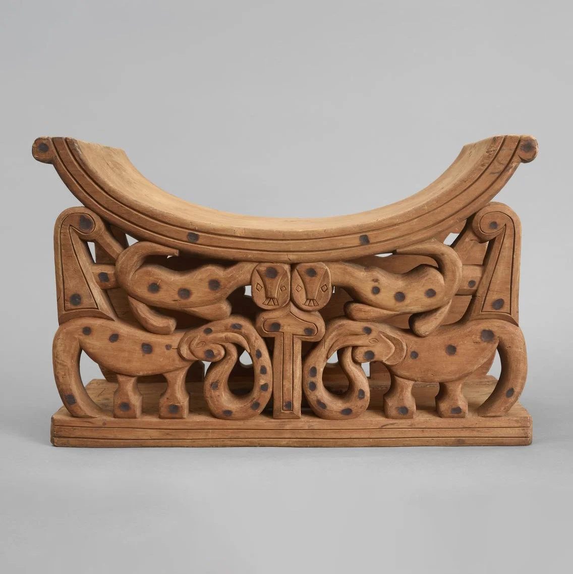 Carved wooden stool, with dished seat supported by leopards standing on the backs of elephants.