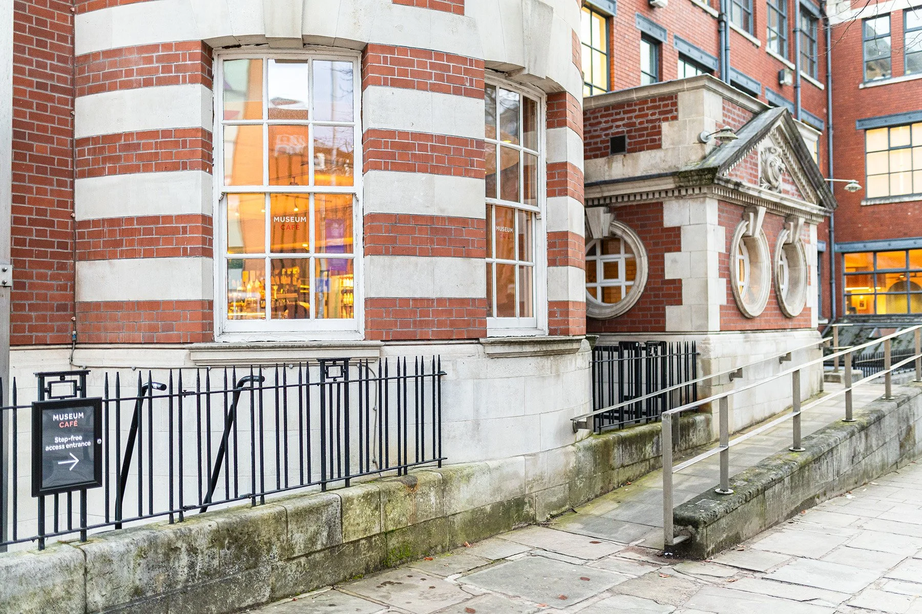 Exterior view of Manchester Museum, at the corner where the Museum Café is located, showing the access ramp to the rear entrance of the Café.