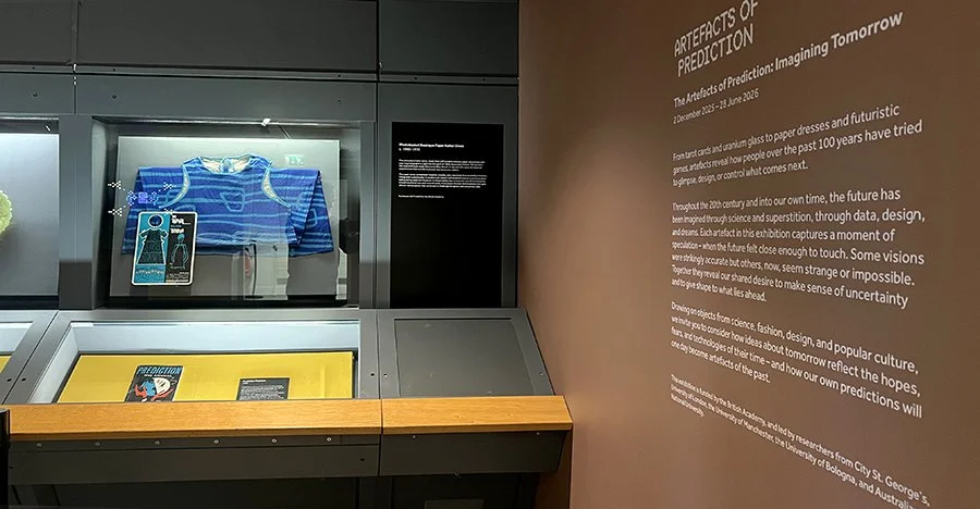 Display case within the exhibition Artefacts of Prediction in the Research Gallery at Manchester Museum. A blue dress is visible in one of the cases.