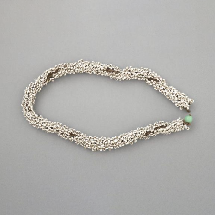 A necklace, consisting of loose coil of white beads. There is a large green bead at either end.
