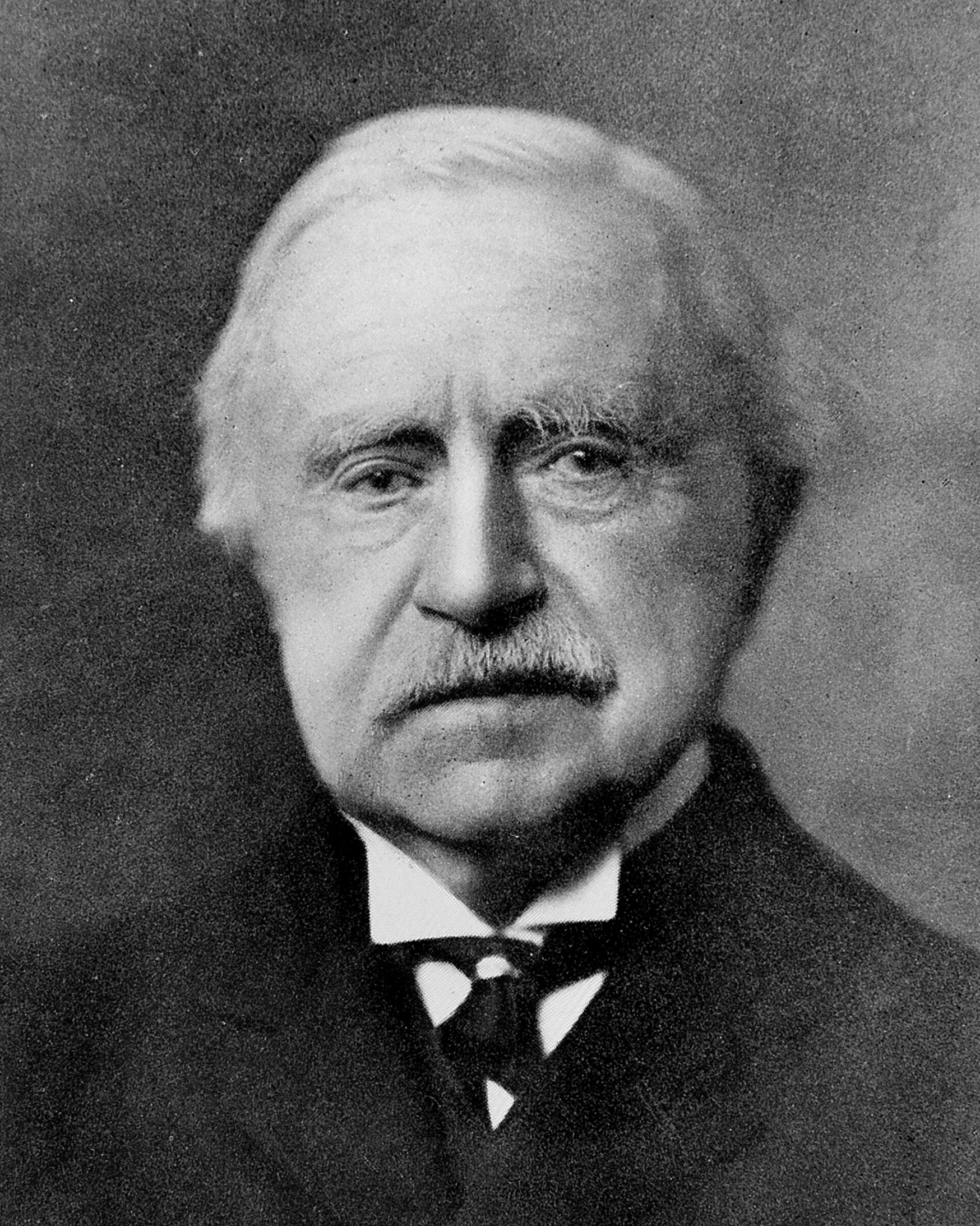 Black and white portrait of an elderly man with white hair, mustache, wearing a suit and tie.