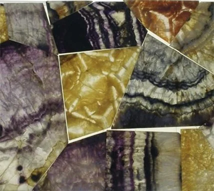 Close-up of various polished stones or minerals with purple, yellow, black, and brown marbled patterns.