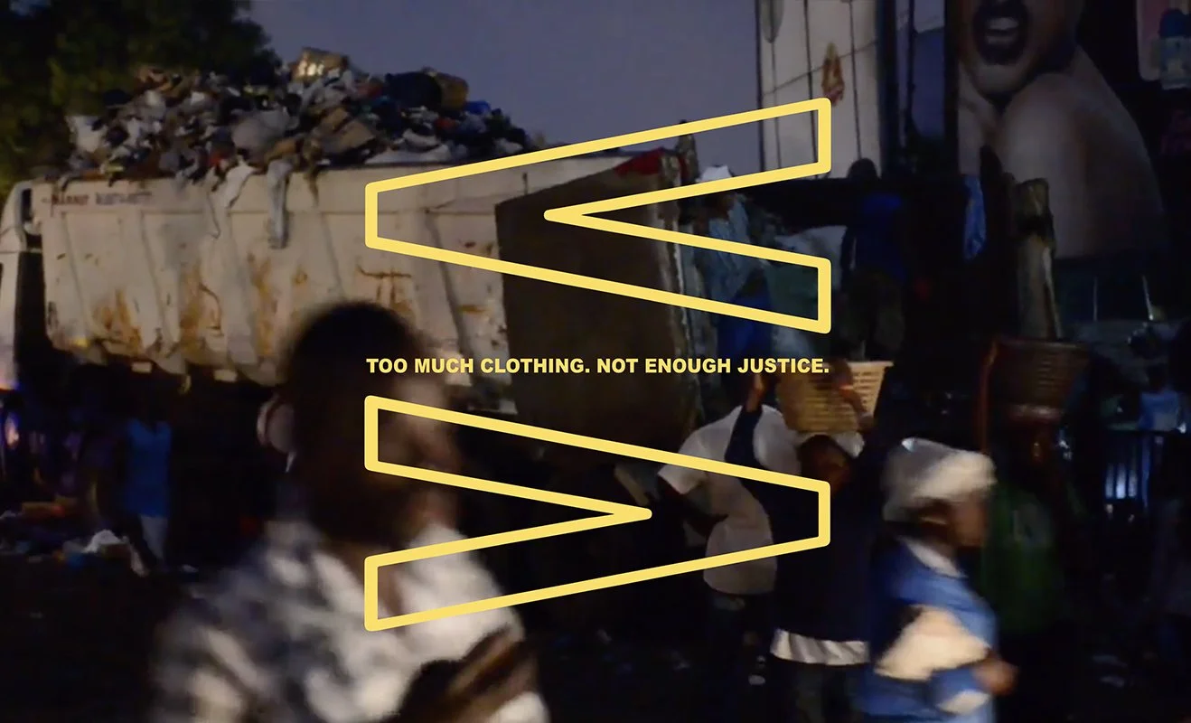 People walking past a truck packed with fabric waste with the words 'too much clothing, not enough justice' superimposed on the image.