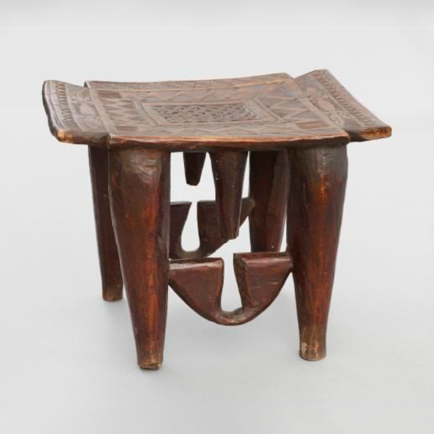 A stool, cut from a single block of hard wood, with four legs. The top is rectangular with the corners cut out.