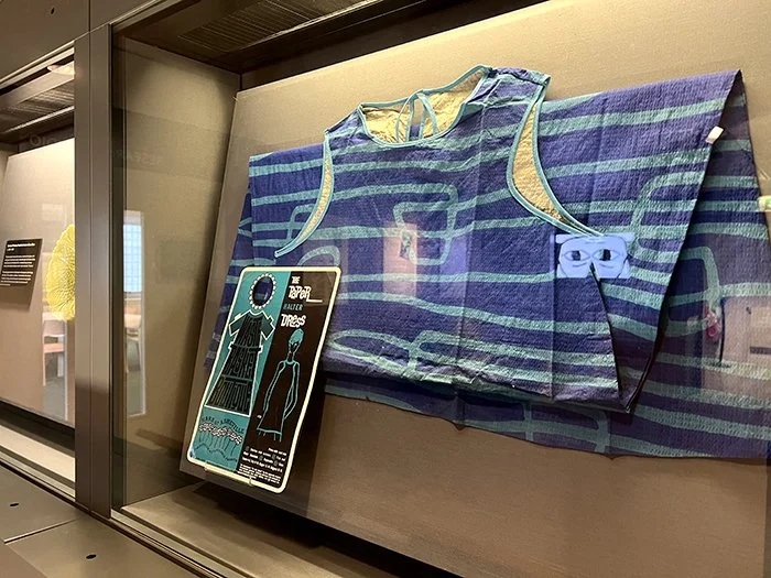 Display case showing a vintage fashion dress within the exhibition Artefacts of Prediction in the Research Gallery at Manchester Museum.