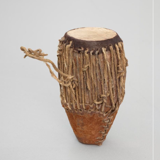 Drum made from a hollow piece of wood covered with a hide. A tympanum of leather is held on by leather strings, with a seed or pebble inside.