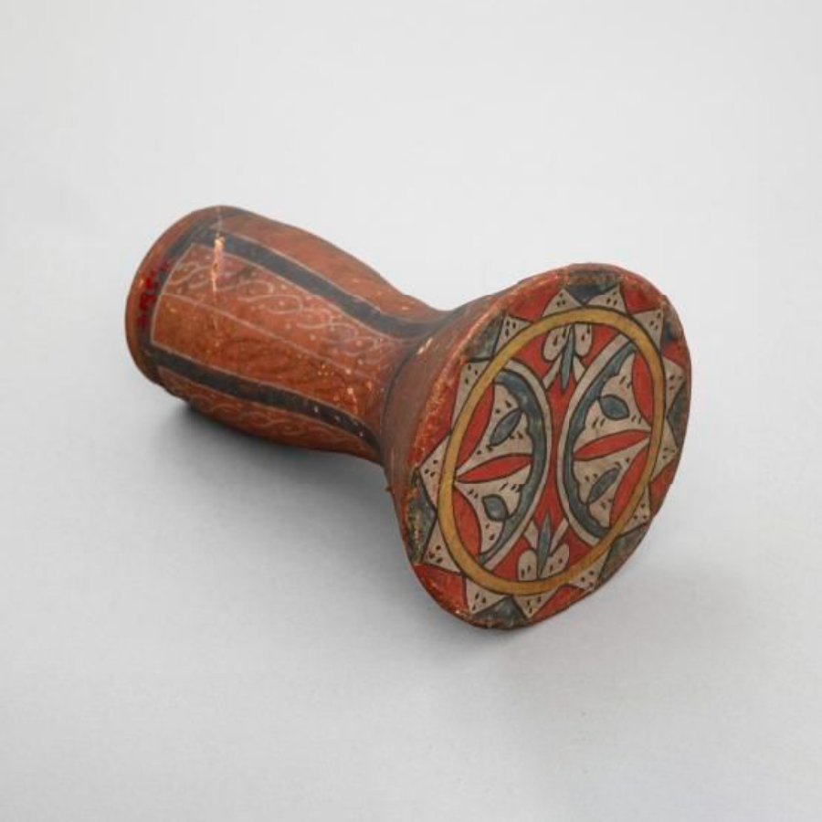 Earthenware drum. Hour glass shape. Parchment membrane, body and membrane painted red, blue and yellow design, made up of segments of circles.