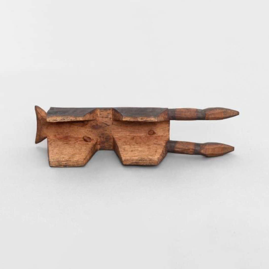 A wooden artefact, possibly a ceremonial sandal. Cut from a single block of wood. Rectangular top with four short, broad, flat legs.