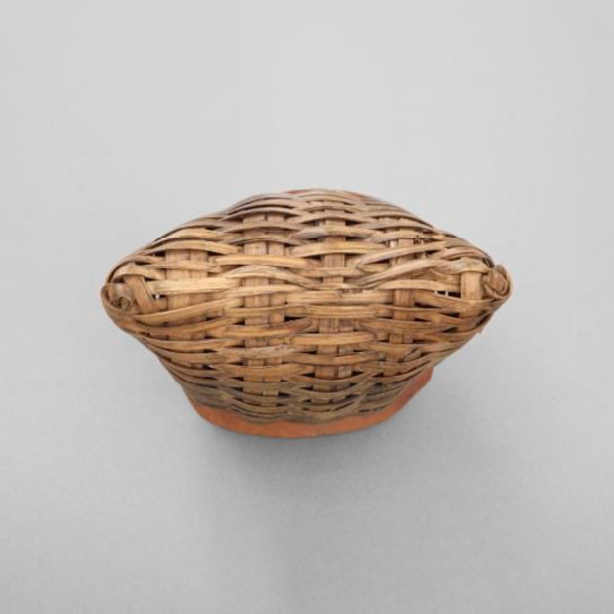 An African rattle. The body is made out of basketwork, with a base made from a section of a large gourd. It is filled with seeds or small stones.