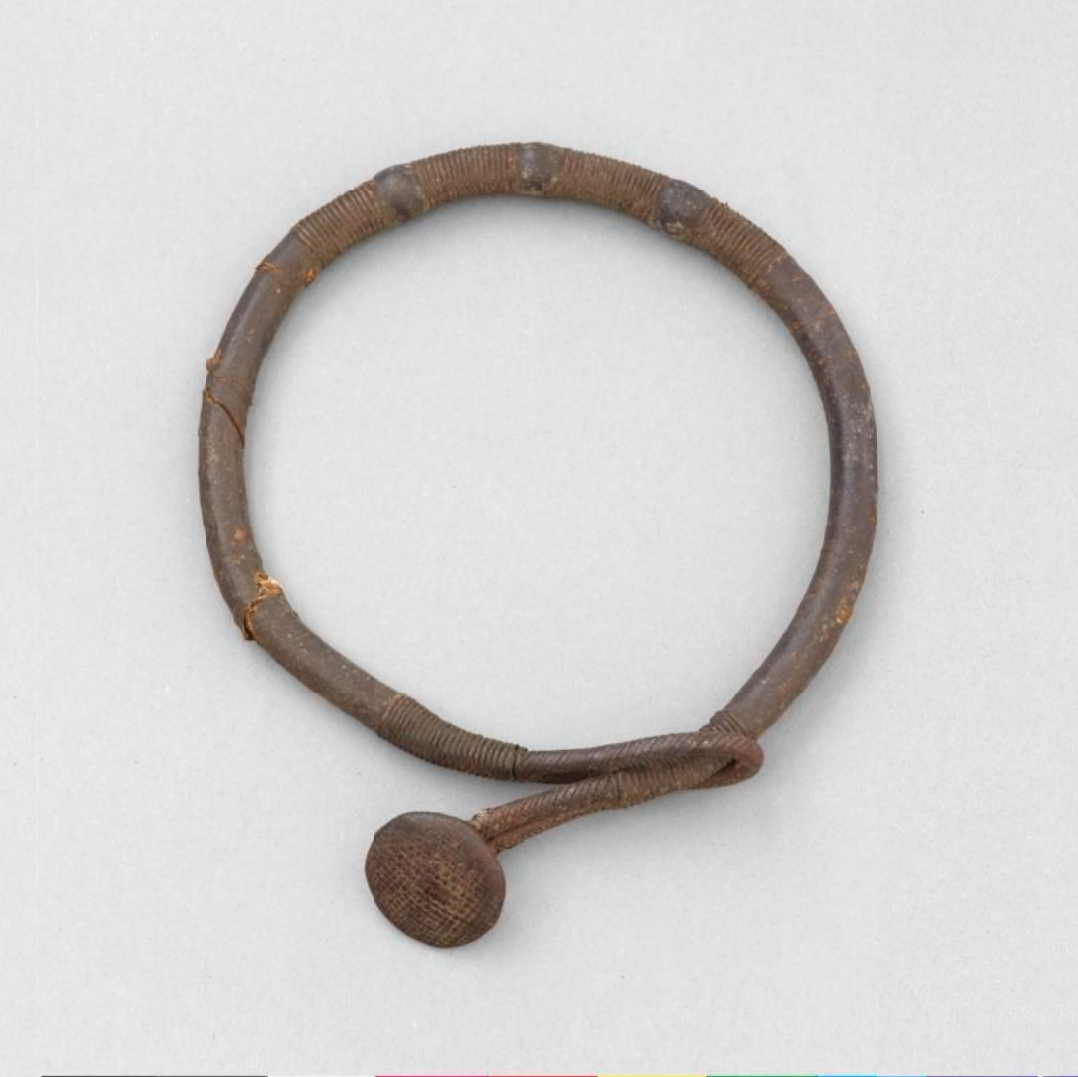 Necklace is made of a leather tube which has been bent into a circle and decorated with coils of leather string.