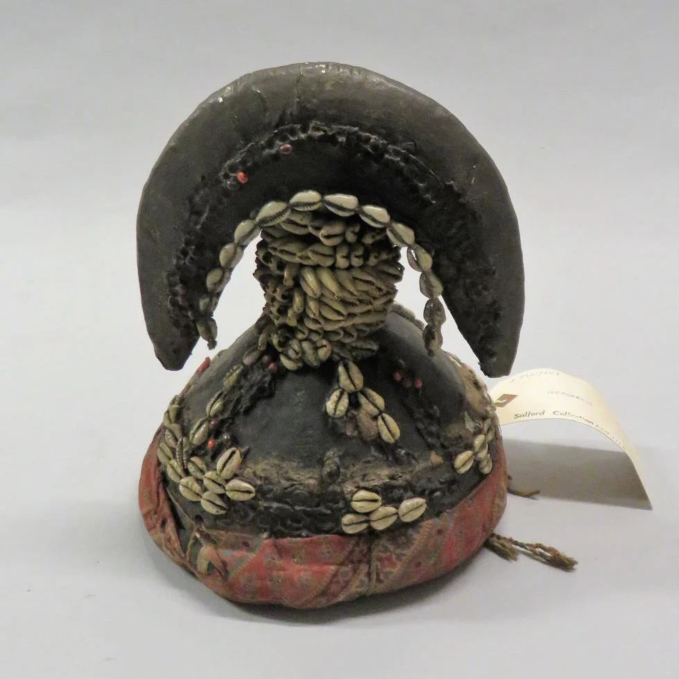 A head-dress featuring a central pillar covered with cowries which supports a horseshoe or crescent.