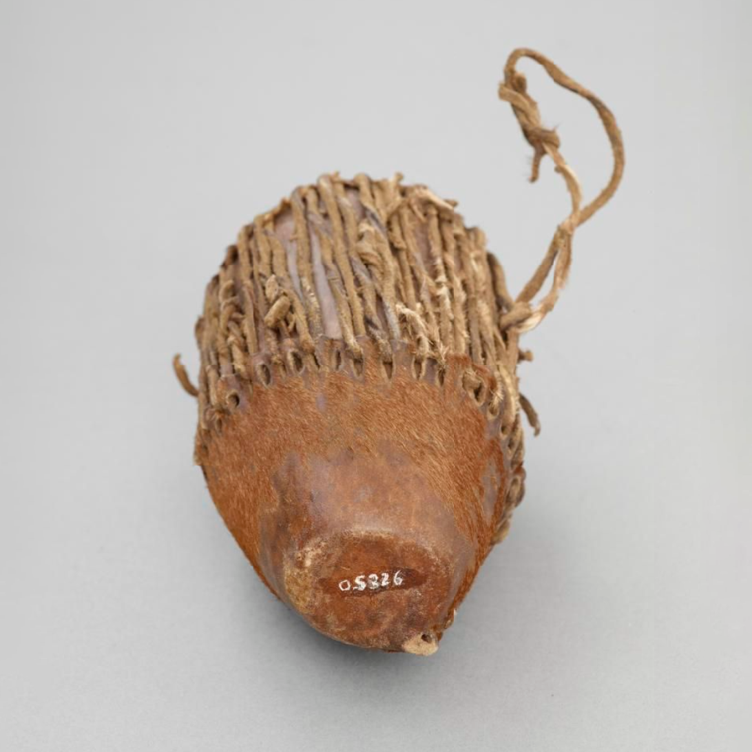 Drum made from a hollow piece of wood covered with a hide. A tympanum of leather is held on by leather strings, with a seed or pebble inside.