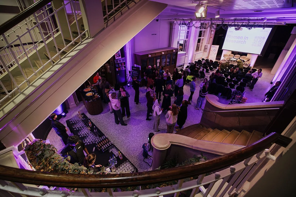 A view of the Main Hall at Manchester Museum from the adjacent staircase, showing people enjoying themselves at a drinks reception.