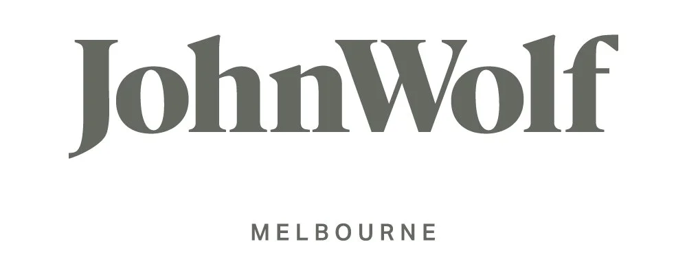 The logo for John Wolf Melbourne, featuring the name "John Wolf" in large gray text and "Melbourne" in smaller gray text underneath.
