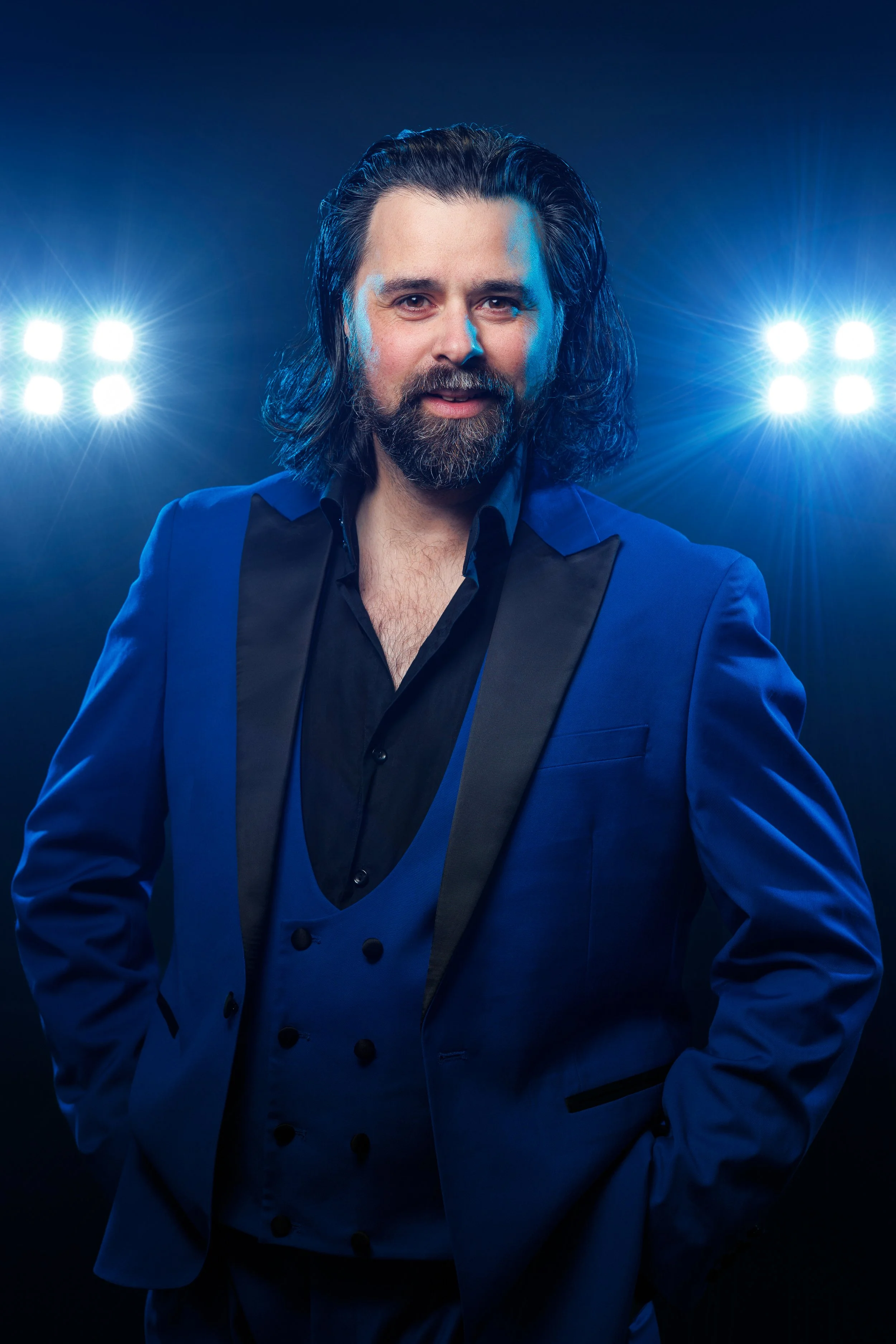Man with beard and long hair tied back, wearing a green shirt, looking directly at the camera.