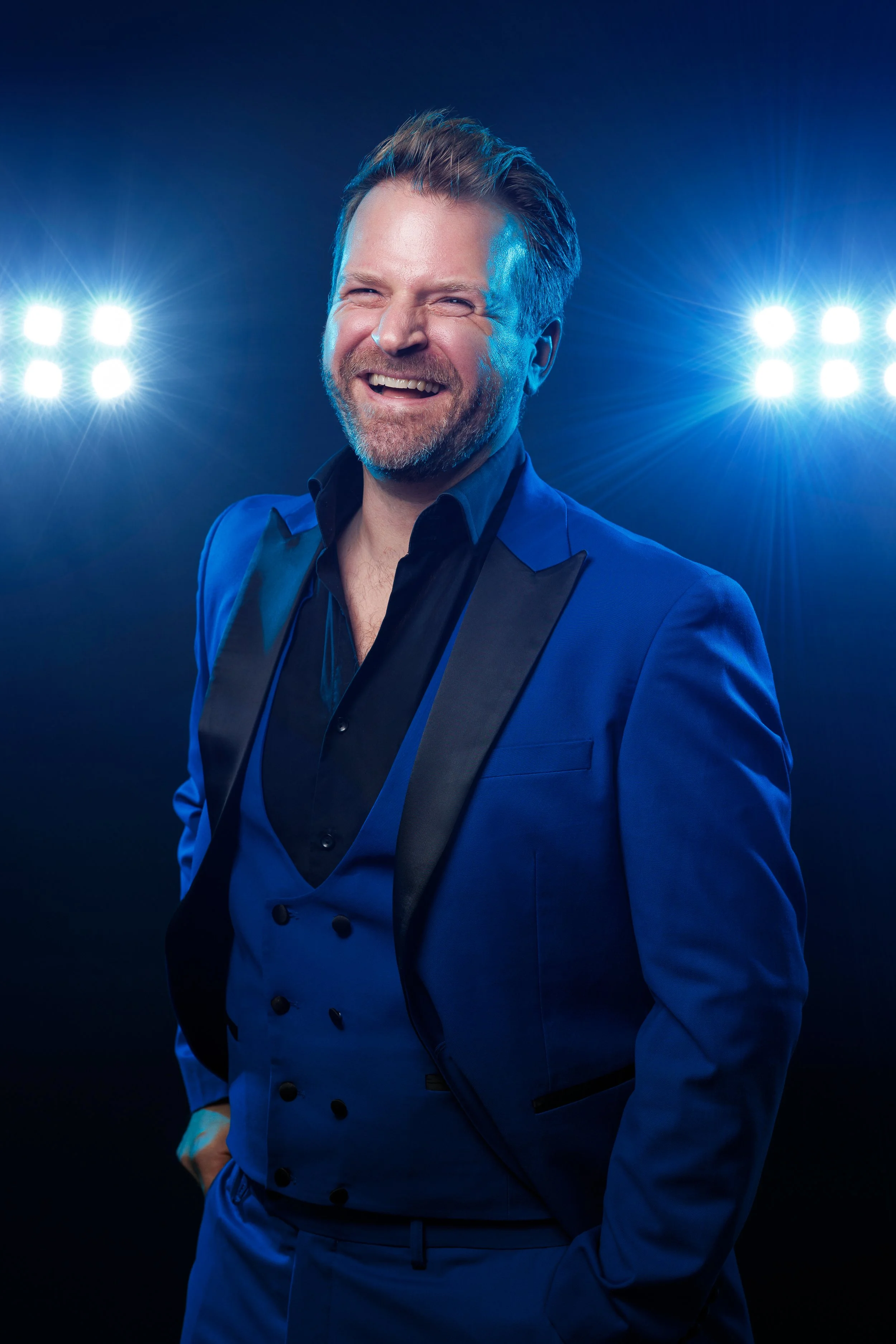 Smiling man with a beard and short hair against a dark background.