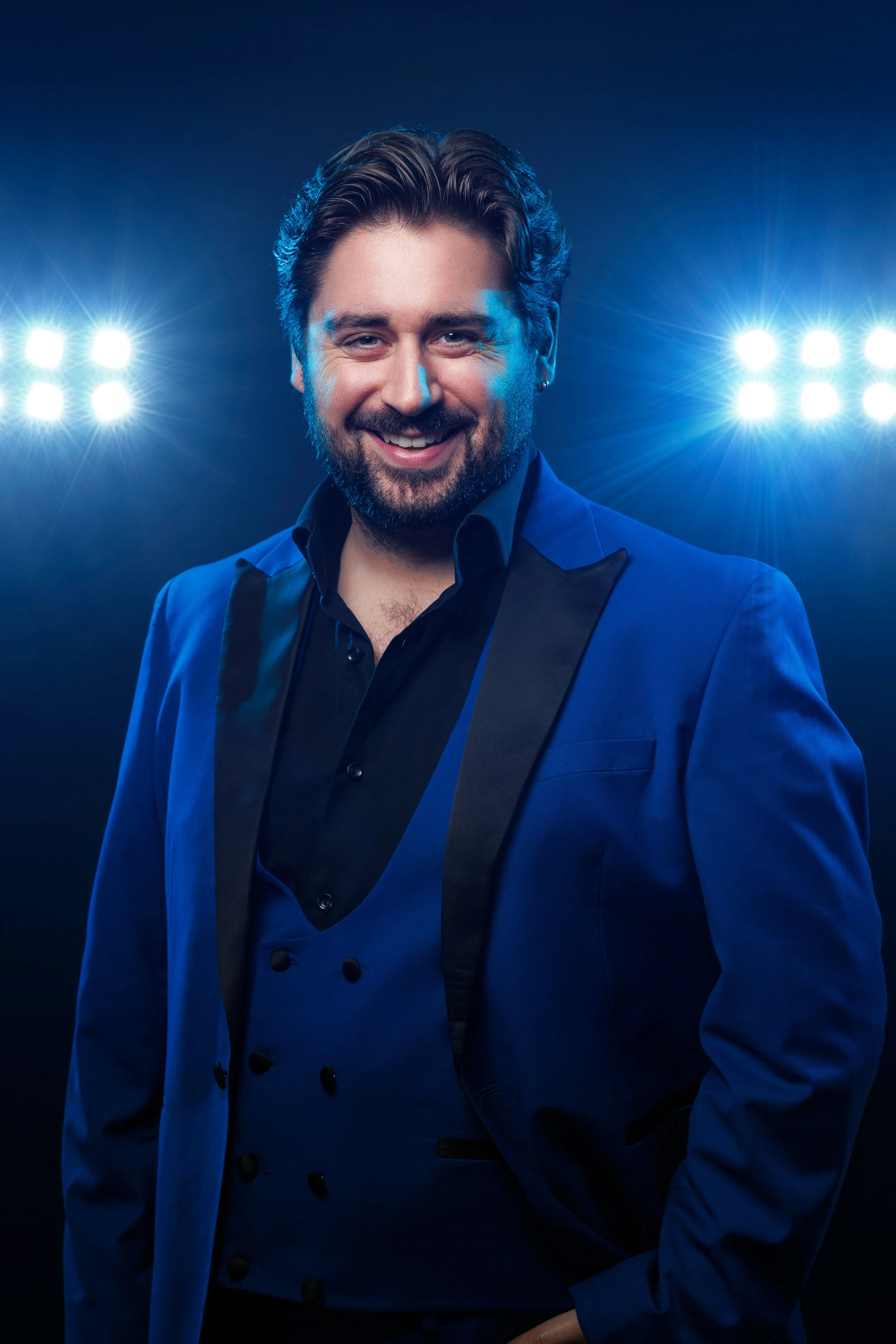 Portrait of a man with a beard and styled hair wearing a blue shirt.