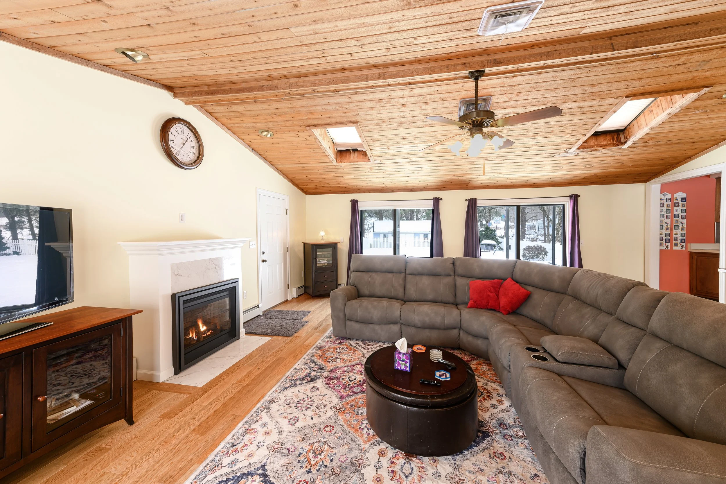 Eric Weiss Photography Connecticut real estate photo of a large family room with fireplace, two sliding glass doors and wood ceiling