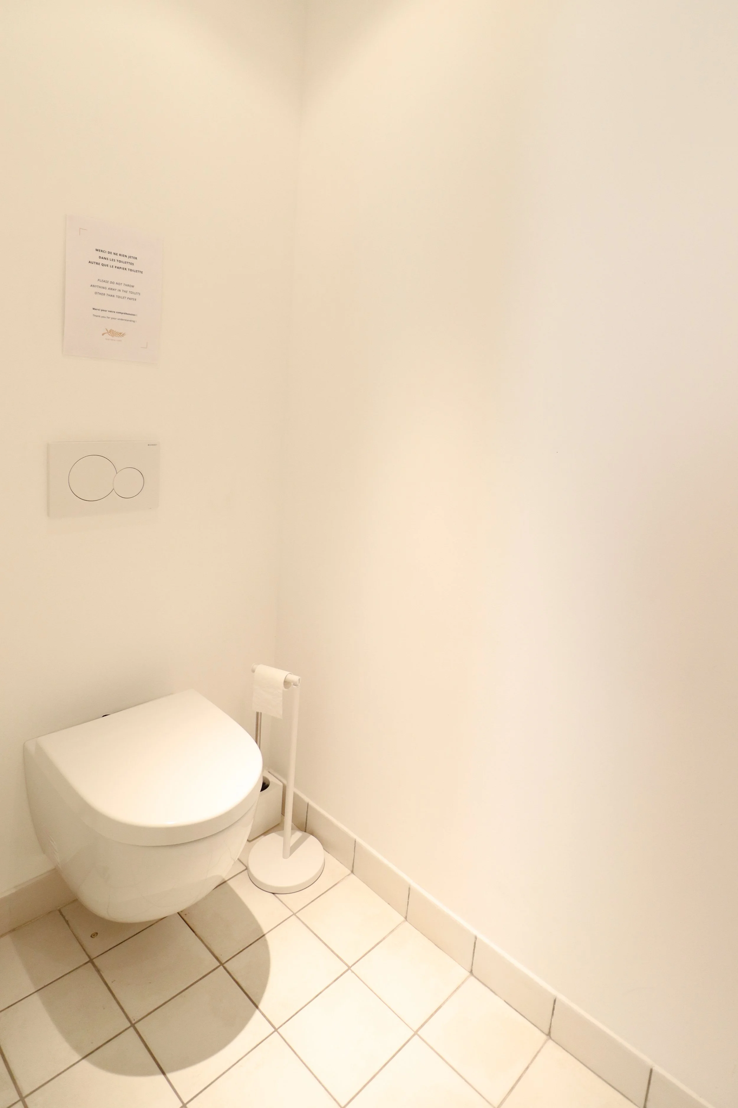 Toilettes dans une salle blanche, comprenant une cuvette et un support de papier toilette.