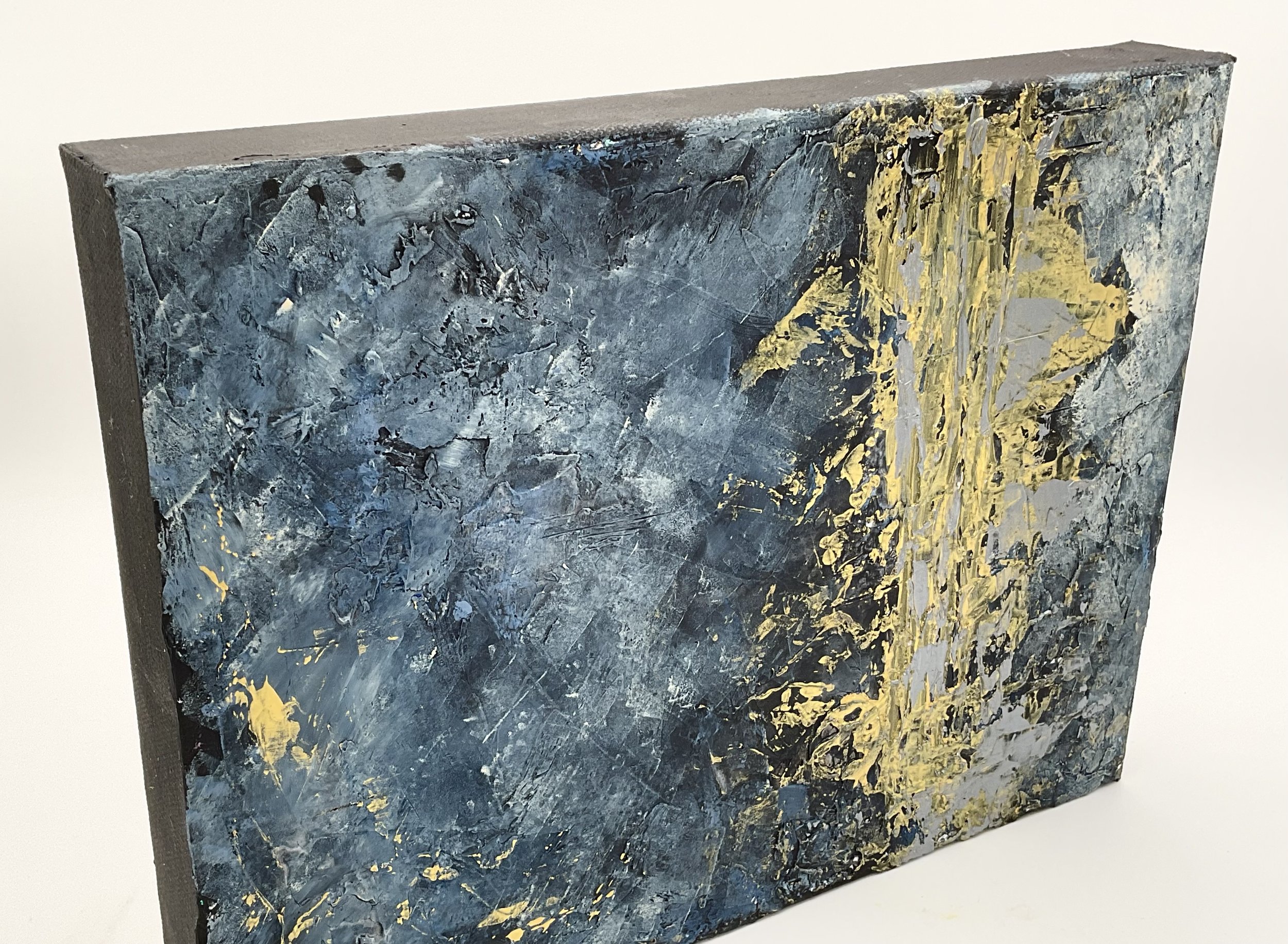 modern mixed media artwork featuring dynamic blue tones with a striking gold streak across. Layered textures imply movement and power, evoking the energy of a wave in motion, or a stormy night sky.