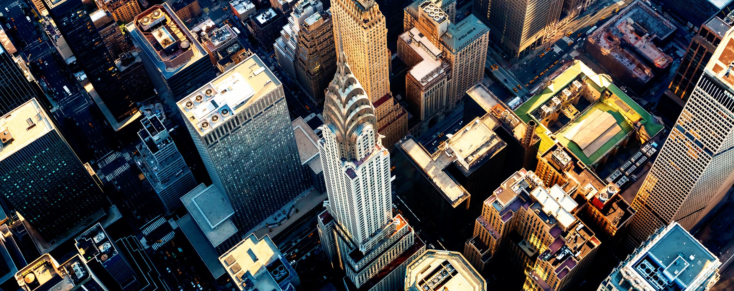 An aerial view of Midtown Manhattan, featuring the iconic Chrysler Building with its distinctive art deco spire, surrounded by other skyscrapers in New York City.