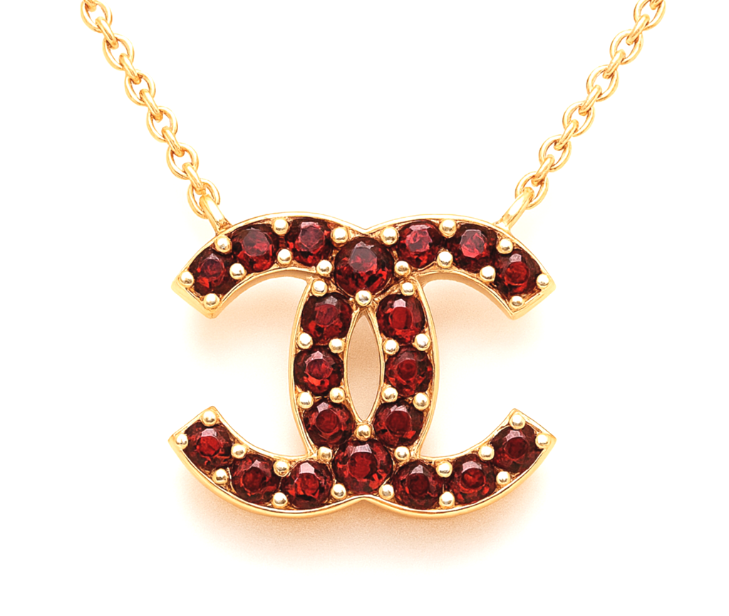 Gold necklace with a pendant shaped like the Chanel logo, decorated with red gemstones.