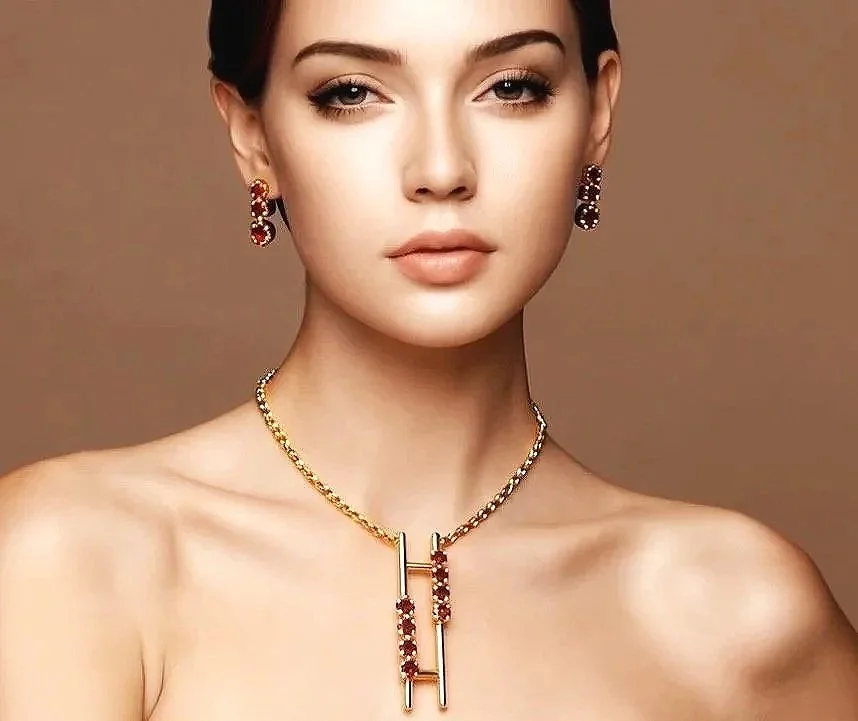 A woman with a neutral expression wearing earrings and a gold necklace with red gemstones and gold bars.