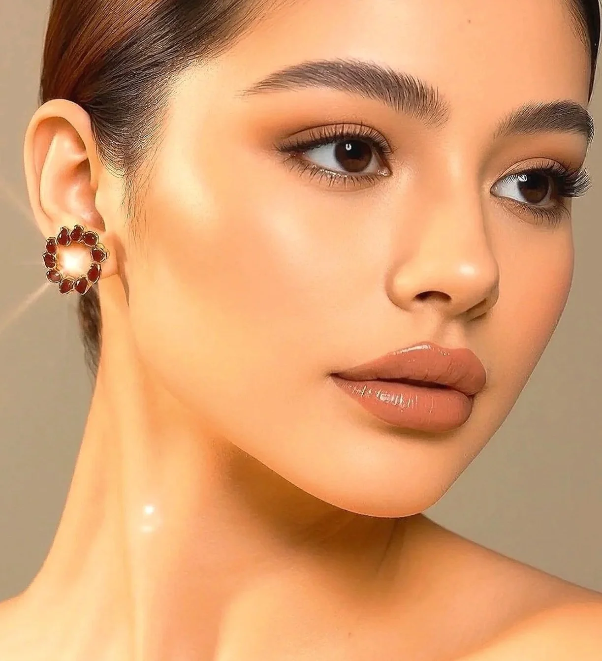 Close-up of a woman's face with makeup, earrings, and smooth skin.
