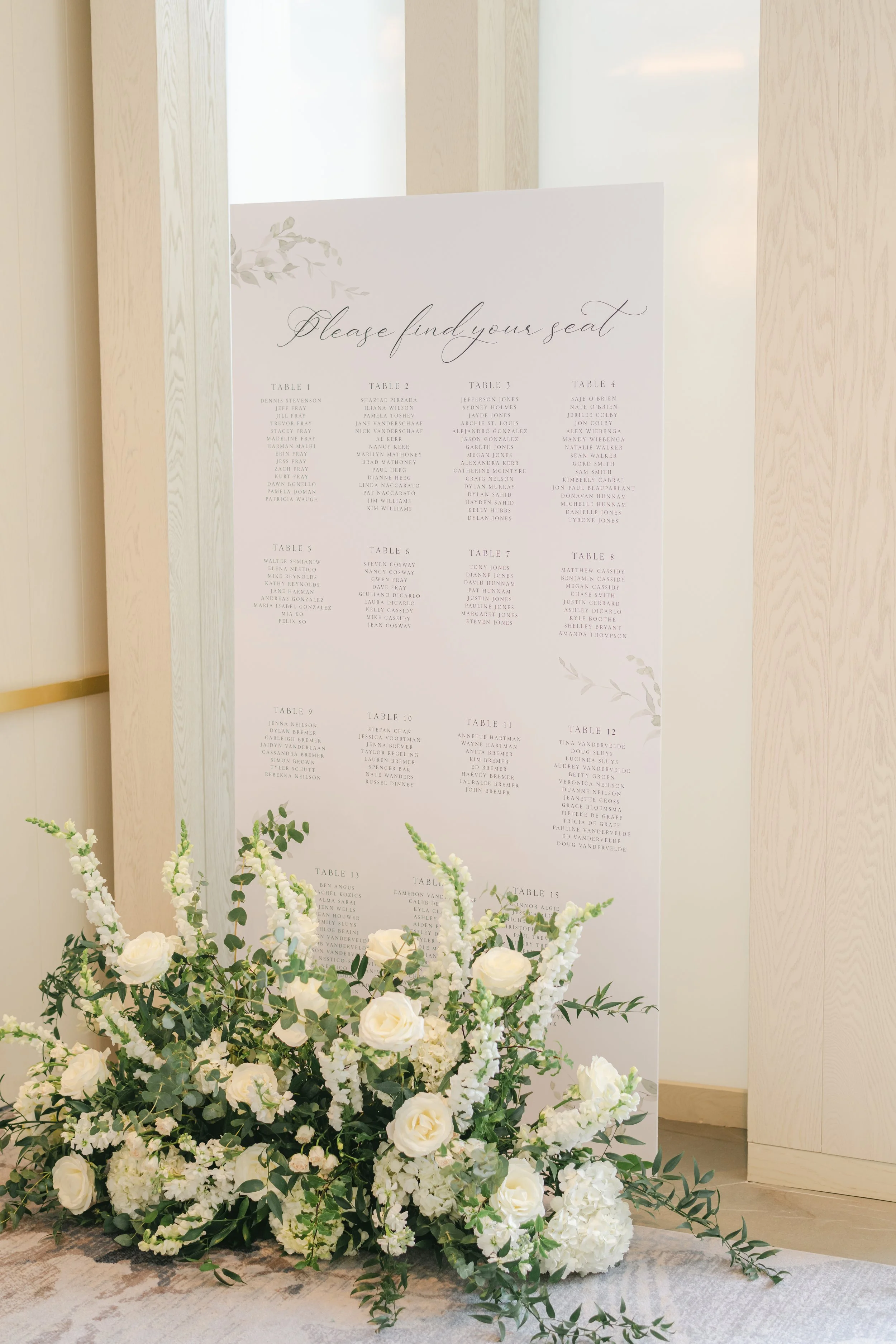 Wedding seating chart sign with floral arrangement in front.