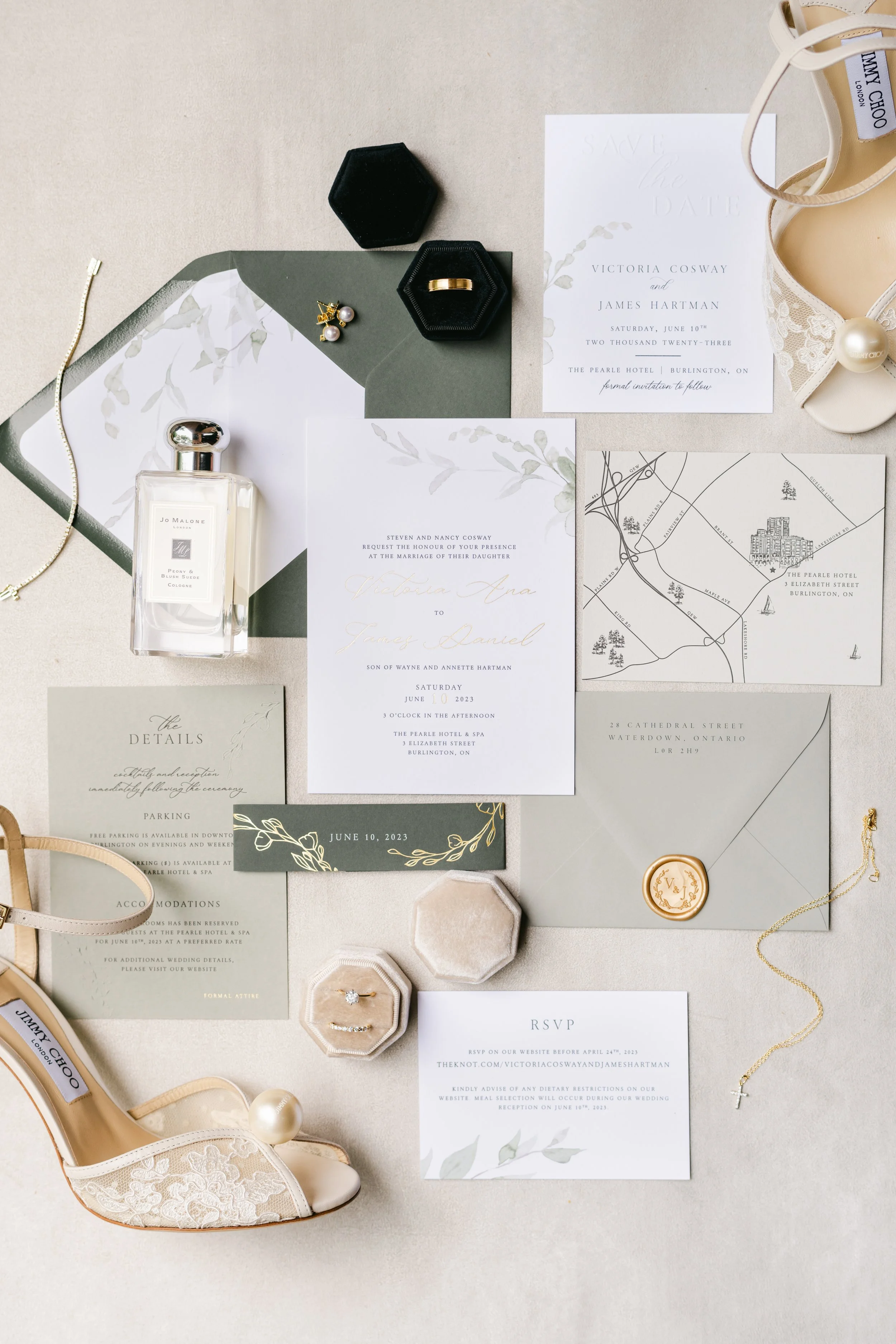Wedding invitation suite with floral details, jewelry, perfume, shoes, and accessories laid out on a light surface.