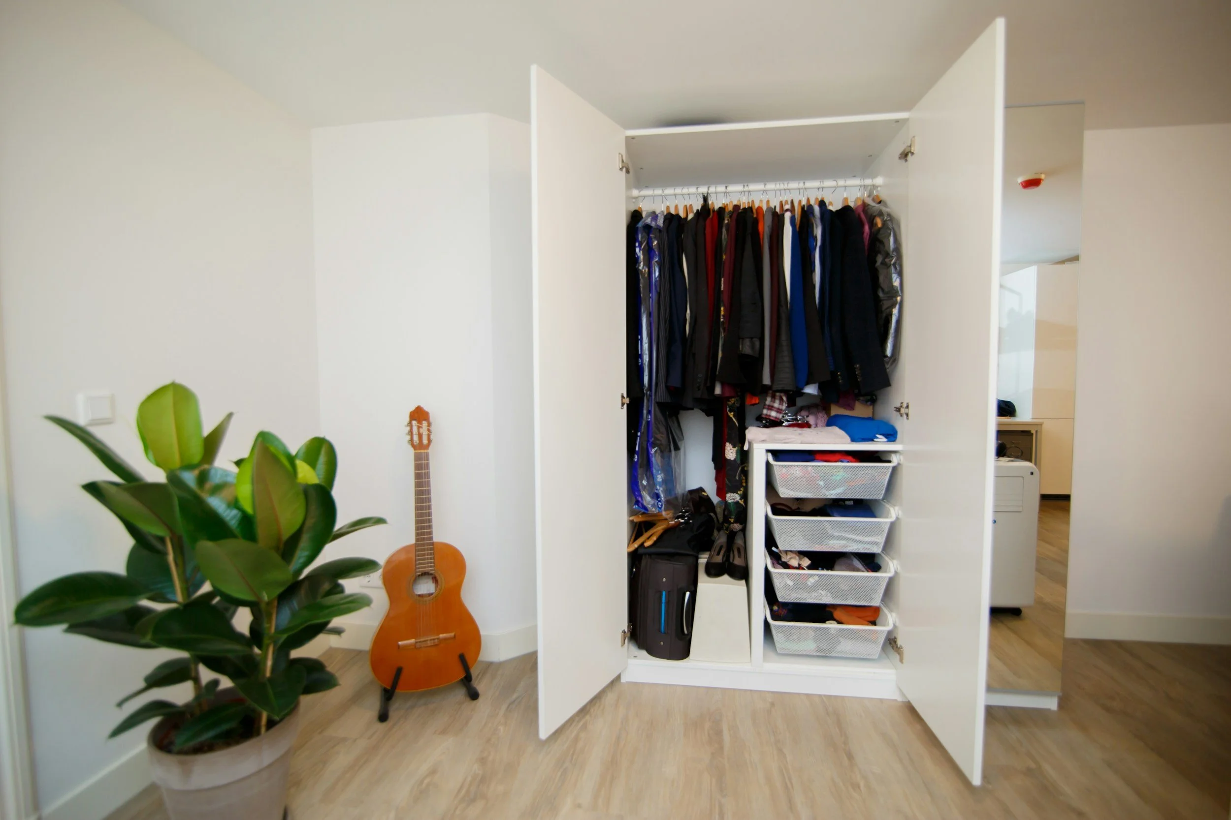 Organized wardrobe closet with hanging clothing, storage drawers, and suitcase space in a St. Louis home