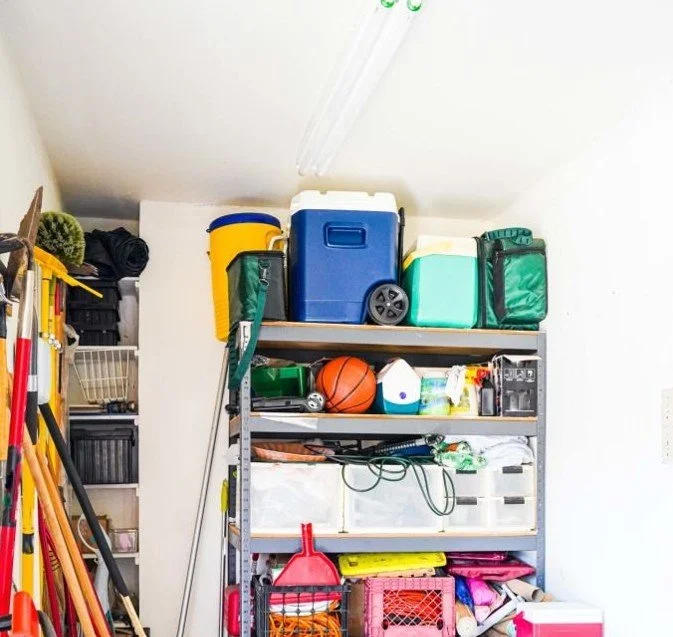 Organized residential garage with shelves holding storage bins, coolers, and sports gear in a St. Louis home