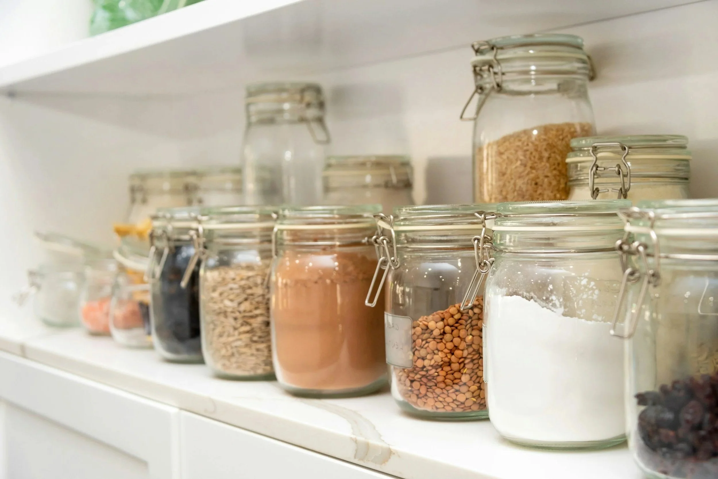 Clear glass pantry containers neatly labeled and arranged for easy food storage in a St. Louis pantry organization project