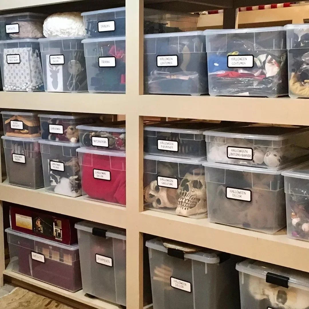Labeled clear storage bins arranged on built-in basement shelves for seasonal and decorative items.